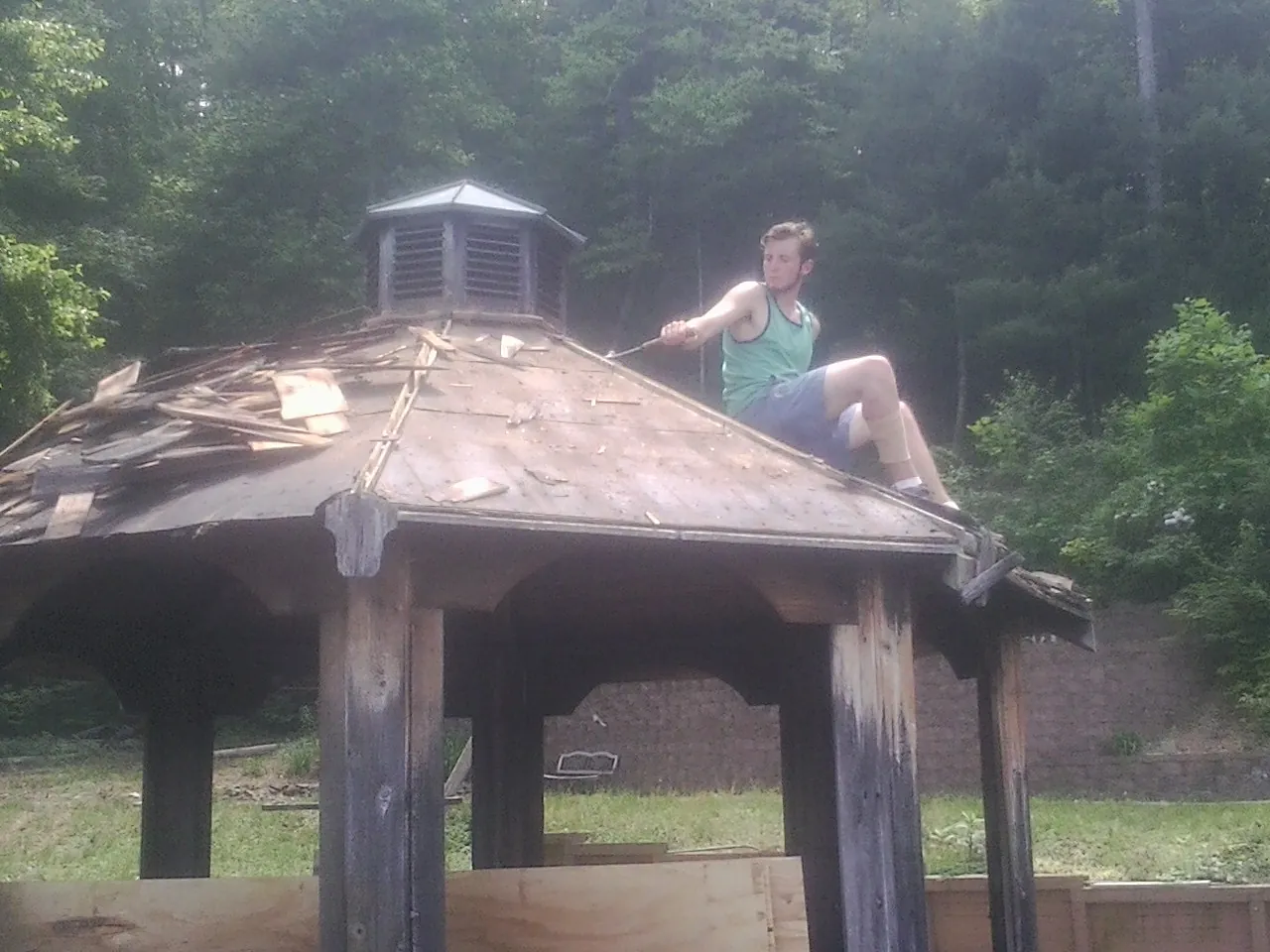 Tearing the old roof off a wooden gazebo before new shakes in Laverne