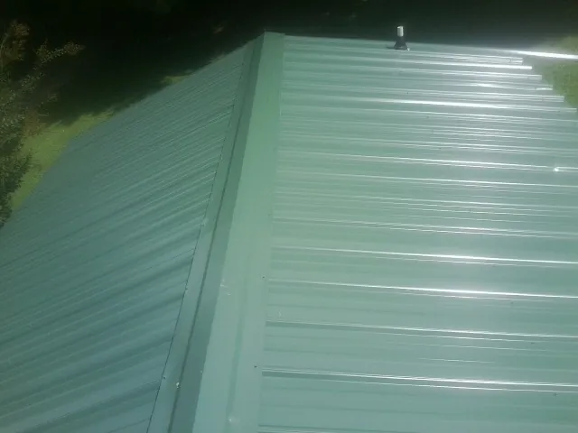 New green metal panels meeting at the ridge of a roof — Flat Roof Repair work by our crew in Laverne