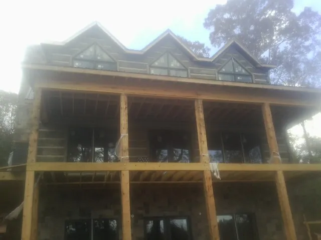 Dormers and porch framing on a large log home under construction — Roof Coating work by our crew in Laverne