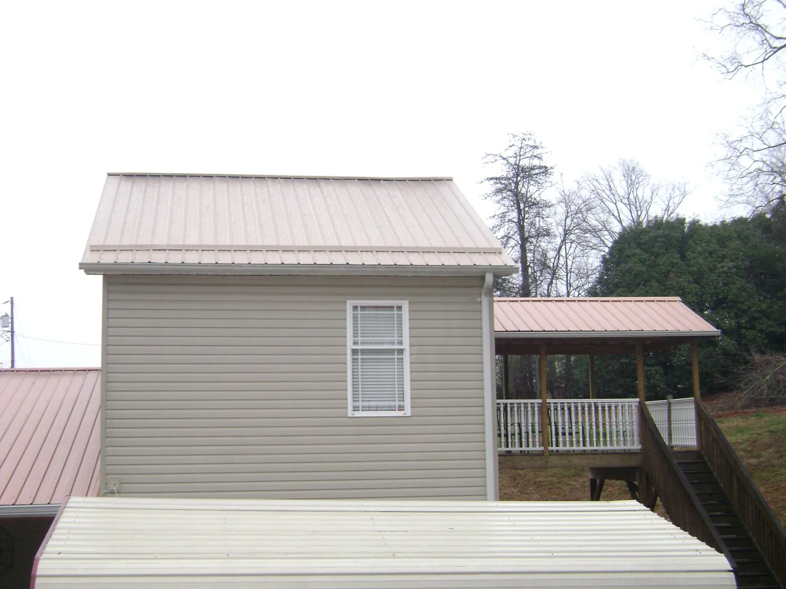 Tan metal roofs on a two story addition and attached porch, from a Roof Replacement job in Laverne