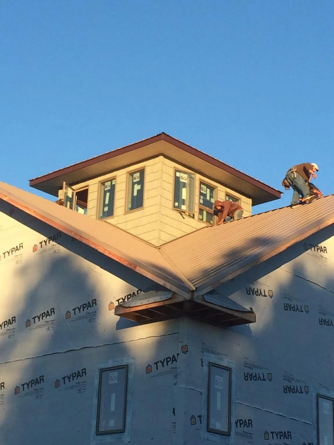 Roofers working around a rooftop cupola on a new metal roof at sunset — Roof Waterproofing in Laverne by Roofing Brothers